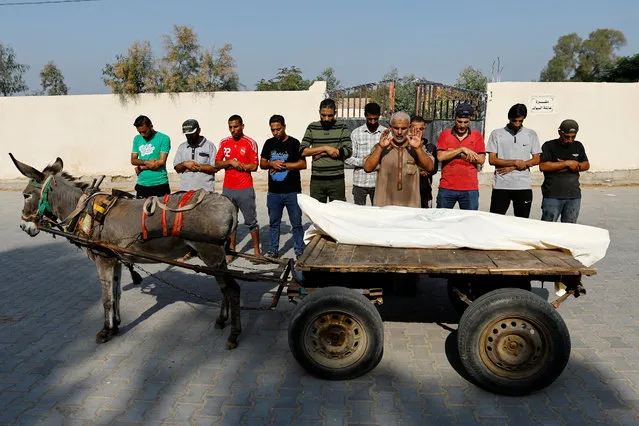 People pray during the funeral of a Palestinian man killed in Israeli strikes whose body is being transported on a donkey-drawn cart, amid shortages of fuel, in Khan Younis, in the southern Gaza Strip on October 25, 2023. (Photo by Ibraheem Abu Mustafa/Reuters)