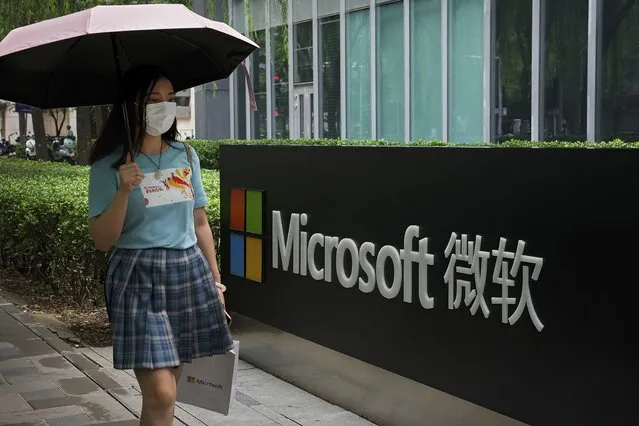 A woman wearing a face mask to help curb the spread of the coronavirus walks by the Microsoft office building in Beijing, Tuesday, July 20, 2021. The Biden administration and Western allies formally blamed China on Monday for a massive hack of Microsoft Exchange email server software and asserted that criminal hackers associated with the Chinese government have carried out ransomware and other illicit cyber operations. (Photo by Andy Wong/AP Photo)
