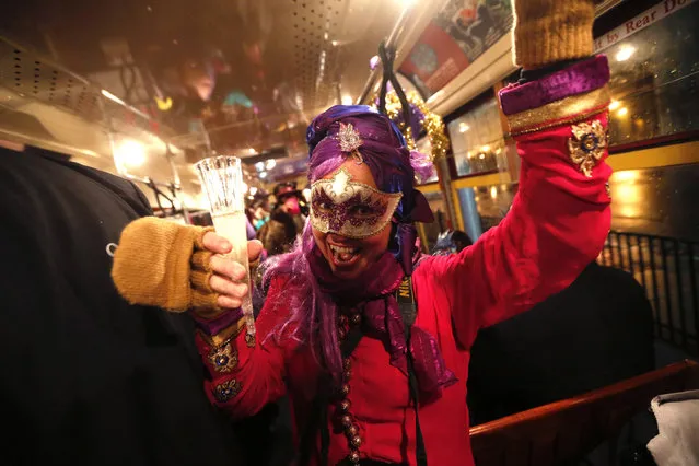 Cheryl Gerber, a member of the “Societe des Champs Elysee” rides the Rampart-St. Claude street car line, which just opened last fall, to commemorate the official start of Mardi Gras season, in New Orleans, Friday, January 6, 2017. Wearing masks and festive costumes, they honored their king and queen at a neighborhood bar and danced as a brass band played “Carnival Time”, before boarding their red street car. (Photo by Gerald Herbert/AP Photo)