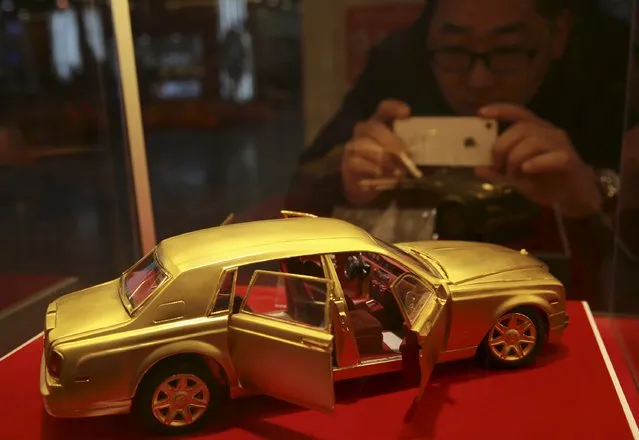 A man takes pictures of a miniature Rolls-Royce model made of gold, on display at a shopping mall in Shenyang, Liaoning province, April 5, 2015. (Photo by Reuters/Stringer)