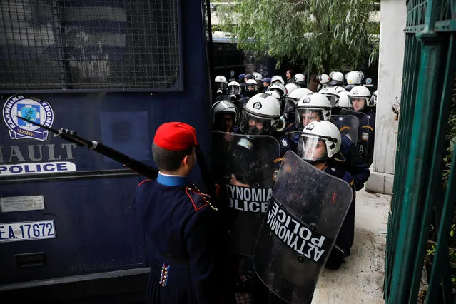 A Greek Presidential Guard returning to his barracks following his sentry duty, stands in front of riot police officers blocking the road leading to the Prime Minister's office during a demonstration of Greek school teachers against government plans to change hiring procedures in the public sector in Athens, Greece, January 11, 2019. (Photo by Alkis Konstantinidis/Reuters)