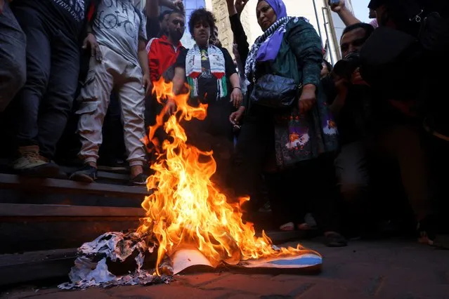 Demonstrators stand near burning banners depicting the Israeli flag as Egyptians protest against Israel and the USA in support of Palestinians for those killed in a blast at Al-Ahli hospital in Gaza that Israeli and Palestinian officials blamed on each other, amid the ongoing conflict between Israel and Hamas, in Cairo, Egypt on October 18, 2023. (Photo by Amr Abdallah Dalsh/Reuters)