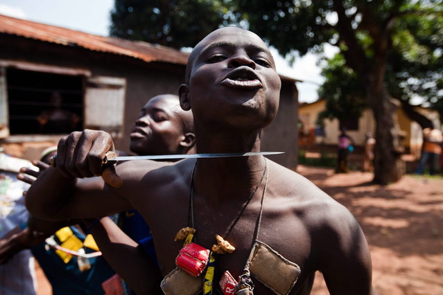 An Anti-Balaka fighter, member of a militia opposed to the Seleka rebel group, puts a knife to his throat showing what he would do to any Seleka, on the outskirts of the Boy-Rabe neighborhood in Bangui on December 14, 2013. France raised alarm on December 13 over worsening violence in the Central African Republic, as UN chief Ban Ki-moon urged warring Christians and Muslims to stop the bloodshed that has left more than 600 dead in the past week. (Photo by Ivan Lieman/AFP Photo)