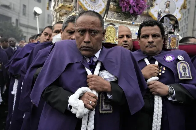 “Cargadores” or carriers, shoulder a religious float supporting The Lord of Miracles religious icon during a procession marking the the nation's patron saint feast day in Lima, Peru, Tuesday, October 18, 2022. After two years of COVID-19 pandemic restrictions, the annual procession has returned to the streets of Lima. (Photo by Martin Mejia/AP Photo)