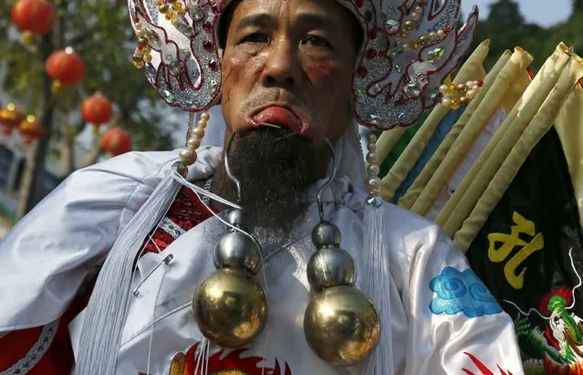 A worshipper with steel hooks pierced through his cheeks takes part in Hei Neak Ta or Spirit Parade, which marks the end of Chinese New Year celebrations in Phnom Penh, Cambodia February 21, 2016. (Photo by Samrang Pring/Reuters)