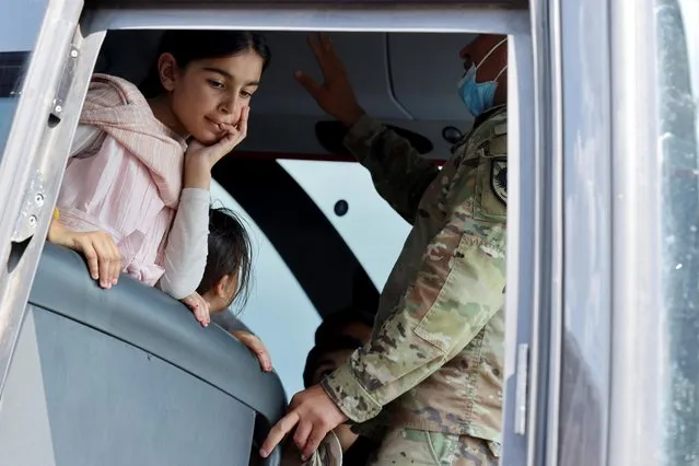 A girl listens to a military interpreter as she and other people arrive at a processing center for refugees evacuated from Afghanistan at the Dulles Expo Center near Dulles International Airport in Chantilly, Virginia, U.S. August 23, 2021. (Photo by Jonathan Ernst/Reuters)
