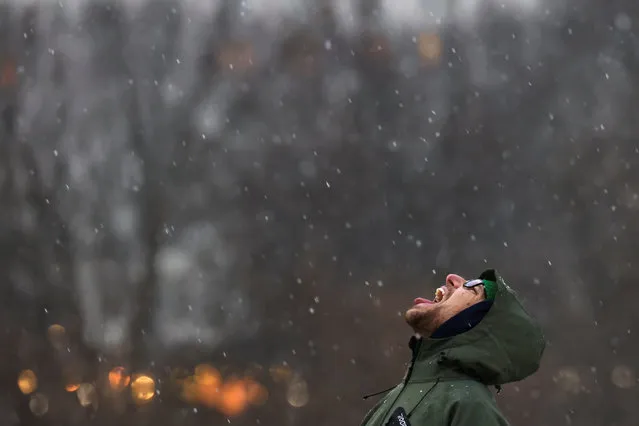 A man looks up with with his mouth open as snow falls in Central Park, New York City on January 6, 2024. (Photo by Andrew Kelly/Reuters)