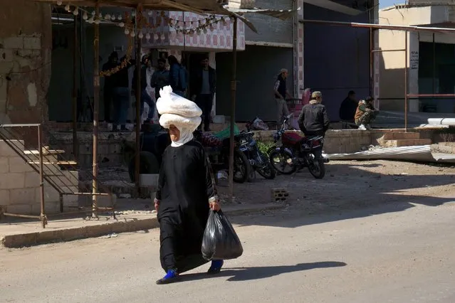 A woman carries bread on her head as she walks along a street in the rebel held al-Ghariyah al-Gharbiyah town, in Deraa province, Syria February 28, 2016. (Photo by Alaa Al-Faqir/Reuters)