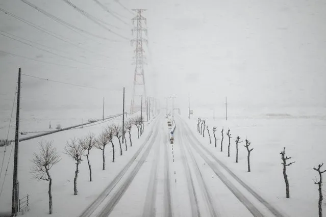 A road is seen during snowfall from a train window along the Tokaido Shinkansen, part of the nationwide high-speed railway network, in Ogaki city of Gifu Prefecture on January 24, 2024. (Photo by Philip Fong/AFP Photo)