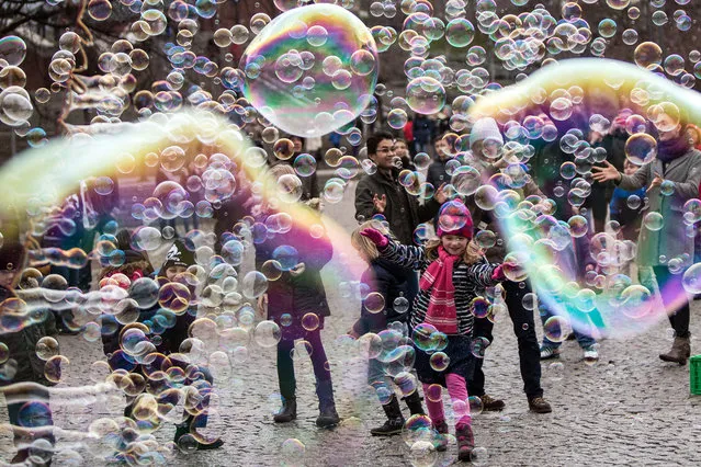Visitors and children play with big and small bubbles in Cologne, Germany, 03 January 2016. The weather in Germany is divided between mild temperatures in the south-west, where as the north of the country is being subject to Siberian cold air. (Photo by Maja Hitij/EPA/EFE)