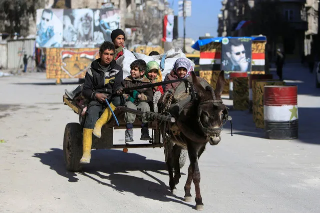 Children ride a donkey cart along a street in Aleppo, Syria February 2, 2017. Pictures of Syria's President Bashar al-Assad are seen in the background. (Photo by Ali Hashisho/Reuters)