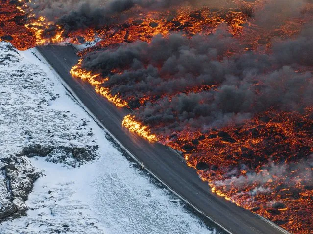 A view of lava crossing the main road to Grindavík and flowing on the road leading to the Blue Lagoon, in Grindavík, Iceland, Thursday, February 8, 2024. A volcano in southwestern Iceland has erupted for the third time since December and sent jets of lava into the sky. The eruption on Thursday morning triggered the evacuation the Blue Lagoon spa which is one of the island nation’s biggest tourist attractions. (Photo by Marco Di Marco/AP Photo)