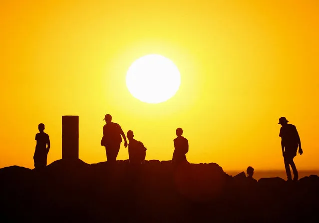 People walk on the rocks during sunset at Sea Point promenade in Cape Town, on January 23, 2024. (Photo by Esa Alexander/Reuters)