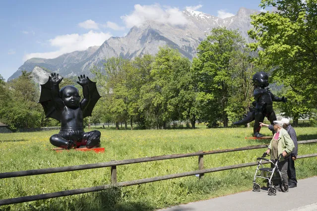 Two men stop looking at the sculptures “Angel Demon3” by Russian artist AES+F, during the 6th Swiss Triennal Festival of Sculpture “Bad RagARTz”, in Bad Ragaz, Switzerland, 07 May 2015. The festival showing about 400 sculptures by 90 artists from 13 countries are shown in public areas from May to November. (Photo by Gian Ehrenzeller/EPA)