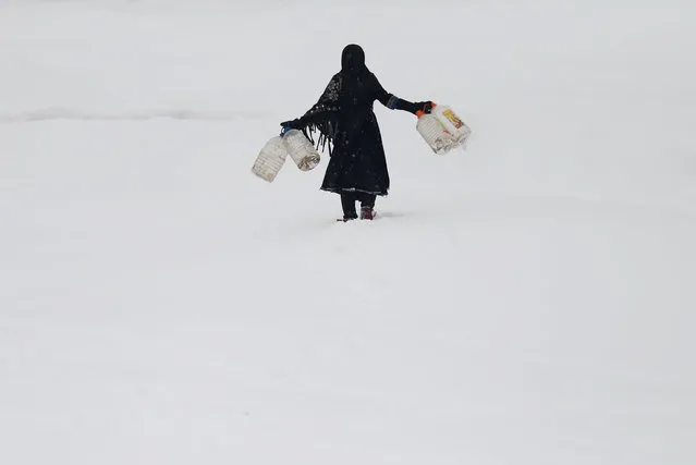 An Afghan girl carries empty water containers during a snowfall in Kabul, Afghanistan February  5, 2017. (Photo by Mohammad Ismail/Reuters)