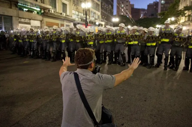 A man confronts riot police during a protest against the upcoming World Cup soccer tournament in Sao Paulo, Brazil, Saturday, February 22, 2014. Hundreds of protesters gathered demonstrating against the billions of dollars being spent to host this year's World Cup while the nation's public services remain in a woeful state. The protest started peacefully, but adherents to the Black Block anarchist tactics vandalized banks and clashed with police, who used tear gas and stun grenades to disperse the violent demonstrators. (Photo by Andre Penner/AP Photo)