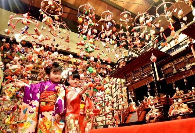 Girls dressed in kimono gaze up at hanging hina dolls at the Bunka Koen Hina no Yakata hall in the Inatori area of Higashi-Izu, Shizuoka Prefecture, on Tuesday, January 20, 2016. Ornaments decorated with the handmade dolls are traditionally displayed in the area for the March 3 celebration of Hina Matsuri, or Doll Festival, to wish for the well-being of girls. (Photo by The Yomiuri Shimbun via AP Images)