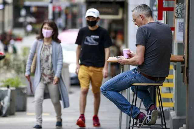 A man sits outside a cafe in central Auckland, New Zealand, Friday, December 3, 2021. Bars, restaurants and gyms reopened in Auckland on Friday as the last major parts of a lockdown that lasted more than 100 days ended. New Zealand has begun a new phase in its virus response in which there won't be lockdowns but people will be required to show vaccine passes for many services. (Photo by Alex Burton/NZ Herald via AP Photo)