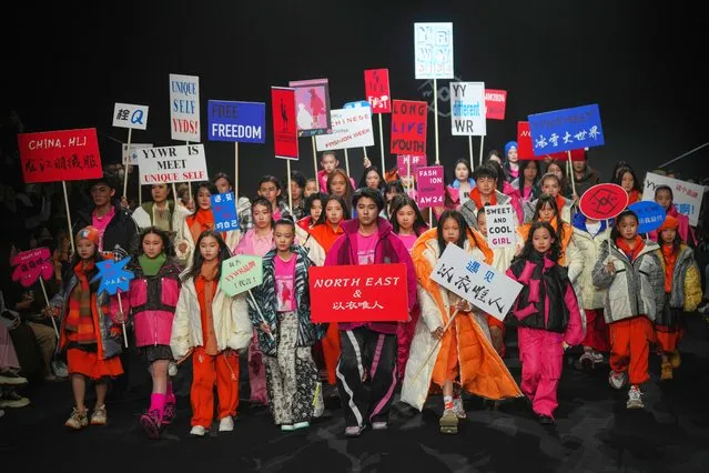 Young models hold placards as they wear creations from YYWR by Jia Xu during the China Fashion Week in Beijing, Sunday, March 31, 2024. (Photo by Tatan Syuflana/AP Photo)