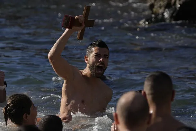 A pilgrim reacts after catching the cross during a water blessing ceremony marking the Epiphany celebrations at Piraeus port, near Athens, Thursday, January 6, 2022. Celebrations to mark the Christian holiday of Epiphany were canceled or scaled back in many parts of Greece Thursday as the country struggles with a huge surge in COVID-19 infections driven by the omicron variant. (Photo by Thanassis Stavrakis/AP Photo)