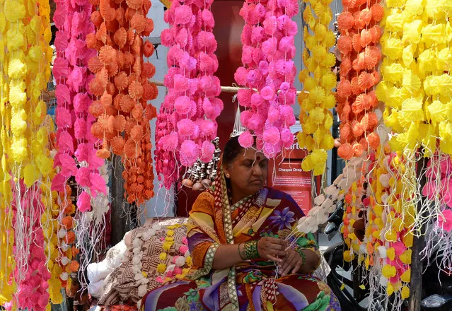 An Indian vendor prepares garlands of traditional sweets made of sugar which are used by Hindu devotees during the celebrations of Holi, on a street in Hyderabad on March 9, 2017. (Photo by Noah Seelam/AFP Photo)
