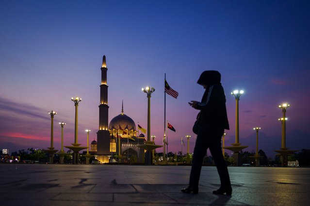 A muslim women walks in front of Putra Mosque during sunset ahead of the holy fasting month of Ramadan in Putrajaya, Malaysia, Monday, March 11, 2024. During Ramadan, Muslims worldwide will observe fasting, abstaining from foods, sеx and smoking from dawn to dusk. (Photo by Vincent Thian/AP Photo)