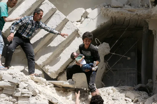 Syrian civil defence volunteers and rescuers remove a baby from under the rubble of a destroyed building following a reported air strike on the rebel-held neighbourhood of al-Kalasa in the northern Syrian city of Aleppo, on April 28, 2016. (Photo by Ameer Alhalbi/AFP Photo)