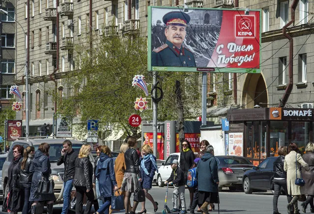 People walk past the poster with WWII Soviet dictator Josef Stalin which was sponsored by local branch of the Communist Party celebrating  Victory Day in Novosibirsk, Russia, Thursday, May 5, 2016, about 2800 kms (1,750 miles) east of Moscow. Russia celebrates victory in WWII on May 9. Scholars estimate that under Stalin more than 1 million people were executed in political purges. Millions more died in the vast prison camp system or as a result of mass starvation and deportations. (Photo by Ilnar Salakhiev/AP Photo)