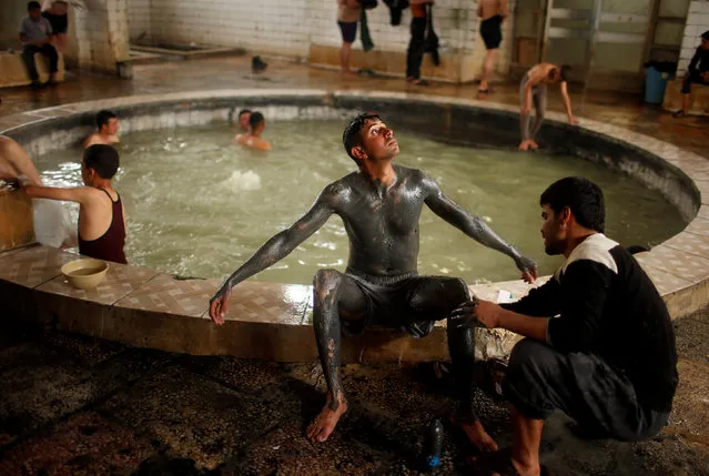 An Iraqi cover his boy with sand from a sulfur pond at Hammam al-Alil city south of Mosul, Iraq April 3, 2017. (Photo by Suhaib Salem/Reuters)