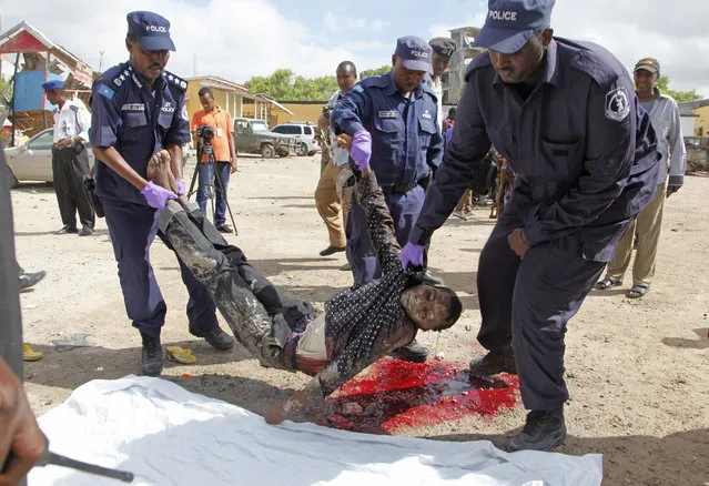 Somali police officers carry the body of a suspected al-Shabab extremist in Mogadishu, Somalia, Monday, May, 9, 2016. (Photo by Farah Abdi Warsameh/AP Photo)