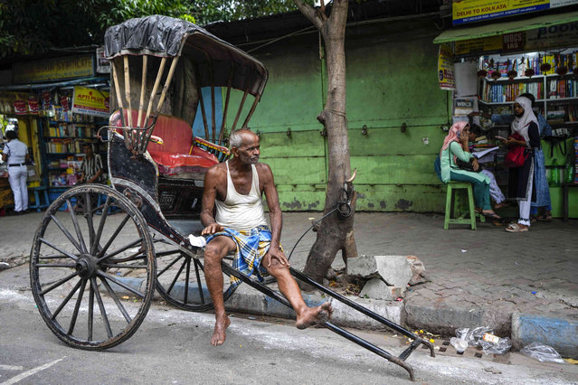 A hand rickshaw puller waits for passengers in Kolkata, India, Wednesday, June 19, 2024. (Photo by Bikas Das/AP Photo)