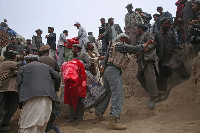 In this Sunday, May 4, 2014 photo, Survivors struggle to receive some donations near the site of Friday's landslide that buried Abi-Barik village in Badakhshan province, northeastern Afghanistan. Stranded and with no homes, many of the families have struggled to get aid. Some have gone to nearby villages to stay with relatives or friends, while others have slept in tents provided by aid groups. The unlucky ones have slept outside. (Photo by Massoud Hossaini/AP Photo)