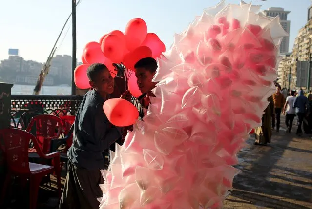 Young boys selling traditional sweets and balloons talk to each other as people celebrate the feast “Eid” which marks the end of the holy fasting month of Ramadan in Cairo, Egypt, July17, 2015. (Photo by Asmaa Waguih/Reuters)