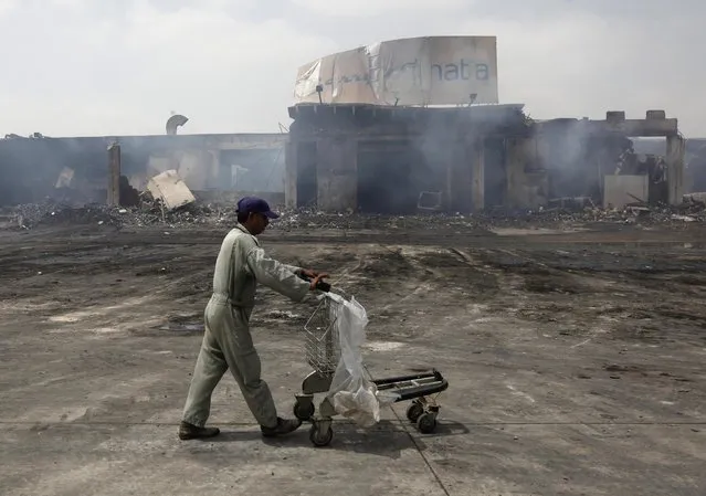 A man pushes a trolley past a damaged building on the tarmac of Jinnah International Airport, a day after Sunday's attack by Taliban militants, in Karachi June 10, 2014. REUTERS/Athar Hussain