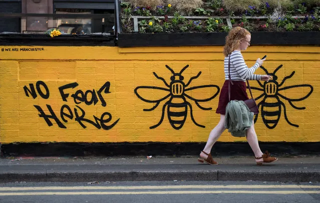 A woman passes a street-art graffiti mural, created following the May 22 terror attack at the Manchester Arena, featuring bees, which are synonymous with Manchester as a symbol of the city's industrial heritage, in Stevenson Square, Manchester, northwest England on May 25, 2017. Britain Thursday closed in on a jihadist network thought to be behind the May 22, 2017 Ariana Grande concert attack, as grief mixed with anger at the US over leaked material from the probe. Britain has raised its terror alert to the maximum level and ordered troops to protect strategic sites after 22 people were killed in a suicide bomb attack on a Manchester pop concert. (Photo by AFP Photo)