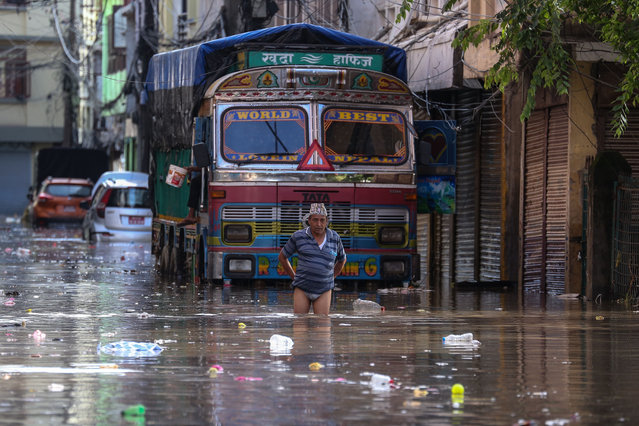 Residents of Kathmandu are wading through the floodwater along the embankment of the Bagmati River flowing through the capital after incessant rainfall overnight on July 31, 2024. Daily life in Kathmandu is going out of gear as heavy downpour is inundating the areas. (Photo by Sanjit Pariyar/NurPhoto/Rex Features/Shutterstock)