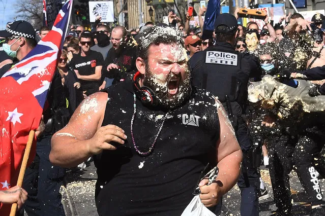 A protester reacts from pepper spray used by police during an anti-lockdown rally in Melbourne on August 21, 2021, amid the city's sixth lockdown to contain a coronavirus outbreak. (Photo by William West/AFP Photo)