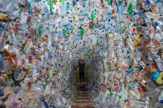 An Indonesian activist from ECOTON (ecological observation and wetland conservation) prepares an installation made with used plastic, including 4,444 bottles, collected from the river in Gresik on September 17, 2021, to raise public awareness of plastic waste in rivers and oceans. (Photo by Juni Kriswanto/AFP Photo)