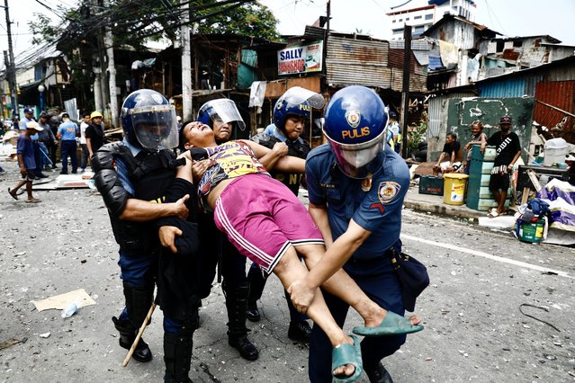 Anti-riot police carry an injured Filipino informal settler during a demolition raid at a shanty town in Pasay City, Metro Manila, Philippines, 01 August 2024. (Photo by Francis R. Malasig/EPA)