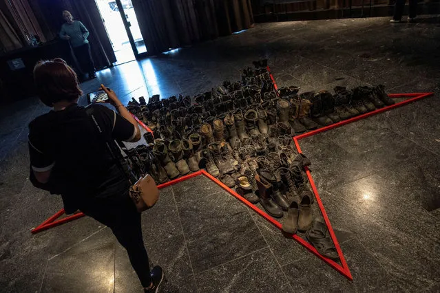 A local resident takes pictures of used boots from Russian soldiers displayed at an exhibition of the Russian invasion of Ukraine at the National Museum of the History of Ukraine in the Second World War, as Russia celebrates Victory Day, which marks the 77th anniversary of the victory over Nazi Germany in World War Two, in Kyiv, Ukraine on May 9, 2022. (Photo by Carlos Barria/Reuters)
