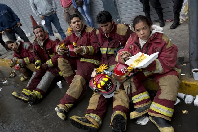 Firefighters take a break from working to extinguish a fire at a warehouse in Lima, Peru, Friday, June 23, 2017. At least 4 people are reported disappeared inside the warehouse according to authorities. (Photo by Rodrigo Abd/AP Photo)
