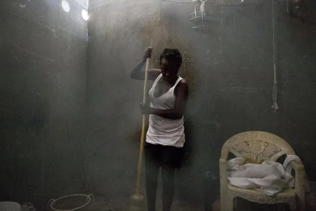 In this June 27, 2015 photo, Neslie Etienne, 28, seen through a hole in mosquito netting, sweeps the room she shares with her husband and six-year-old son in an abandoned shipping container in Port-au-Prince, Haiti. Forced evictions and rental subsidies cleared many of the camps that had been set up for those displaced by the 2010 earthquake, but didn't provide long-term solutions for those left homeless by the quake. (Photo by Rebecca Blackwell/AP Photo)