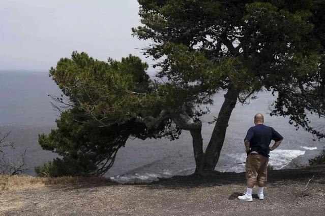 An onlooker stands near an ocean cliff in Palos Verdes Estates, Calif., Monday, May 23, 2022. Four people fell off a Southern California ocean cliff in the early morning darkness on Monday and a man was killed and two women were critically injured, authorities said. (Photo by Jae C. Hong/AP Photo)