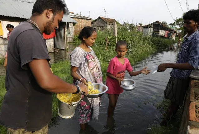 Relief workers distribute cooked food to villagers surrounded by flood water at Khudirabad village near Kolkata, West Bengal state, India, Monday, August 3, 2015. (Photo by Bikas Das/AP Photo)