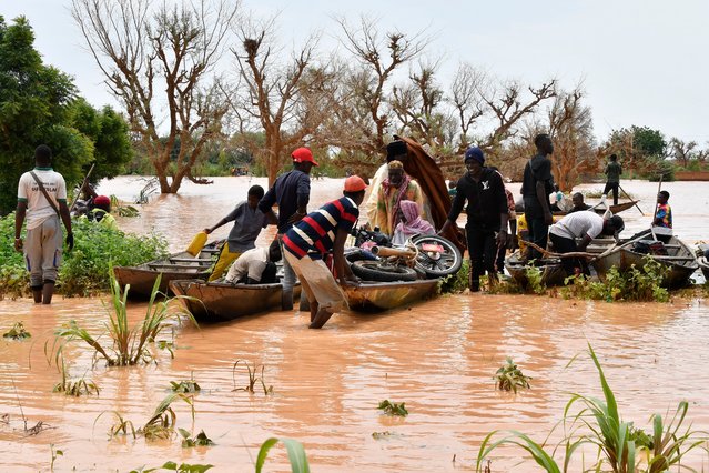 This photograph take on August 20, 2024 shows locals preparing canoes to carry people following heavy rains that damaged National Road 25 from the Nigerien capital Niamey to the provinces of Tillabéri and Tahoua in western Niger. The rainy season from June to September regularly brings a heavy death toll. In 2022 there were 195 deaths and 400,000 people affected. (Photo by Boureima Hama/AFP Photo)