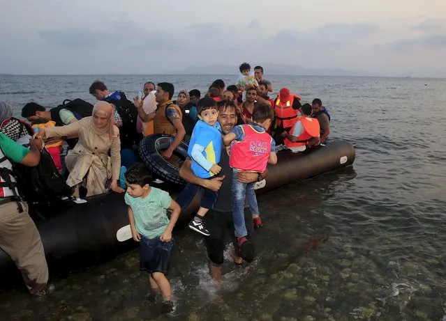 Syrian refugees from Kobani jump off a dinghy as they arrive at a beach on the Greek island of Kos, after crossing a part of the Aegean sea from Turkey, August 10, 2015. (Photo by Yannis Behrakis/Reuters)