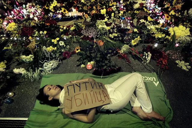 A Ukrainian woman lies down in front of the Dutch embassy in Kiev, holding a poster reading “Putin is a killer”, on Jule 17, 2014. A Malaysian Airlines passenger jet was shot down in eastern Ukraine on Thursday, and both the Ukrainian government and pro-Russian rebels blamed one another for the attack. (Photo by Sergei Chuzavkov/Associated Press)