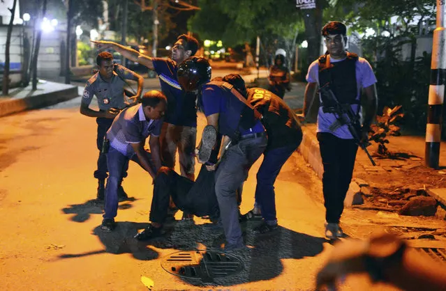 People help an unidentified injured person after a group of gunmen attacked a restaurant popular with foreigners in a diplomatic zone of the Bangladeshi capital Dhaka, Bangladesh, Friday, July 1, 2016. A group of gunmen attacked a restaurant popular with foreigners in a diplomatic zone of the Bangladeshi capital on Friday night, taking hostages and exchanging gunfire with security forces, according to a restaurant staff member and local media reports. (Photo by AP Photo)