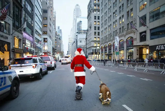 A man dressed as Santa Claus skateboards down Fifth Avenue towing a dog before the annual Christmas tree lighting ceremony at Rockefeller Center in New York on December 5, 2019. (Photo by John Angelillo/UPI/Barcroft Media)