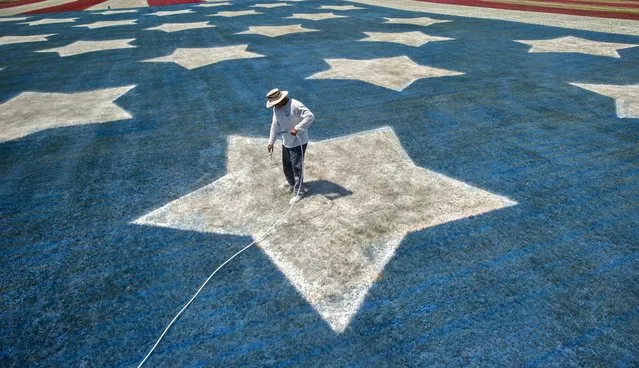 Dano Byrd puts a second coat of paint on a star of a giant American flag Saturday, July 2, 2016, on the field in front of the Burr family home in Bowling Green, Ky. The flag took 700 gallons of paint and over 120 hours to lay out the design.  The project started in 2002, in honor of the Sept. 11, 2001, terrorist attacks. It continued for 10 years, before taking a break after 2012. (Photo by Miranda Pederson/Daily News via AP Photo)
